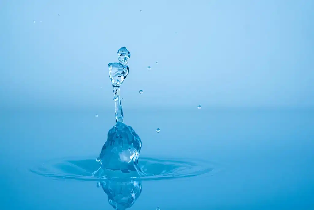 Water drop splashing into blue water surface